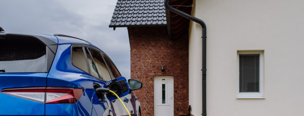 Close-up of electric car charging near a family house.