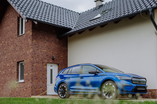 Close-up of electric car charging near a family house.