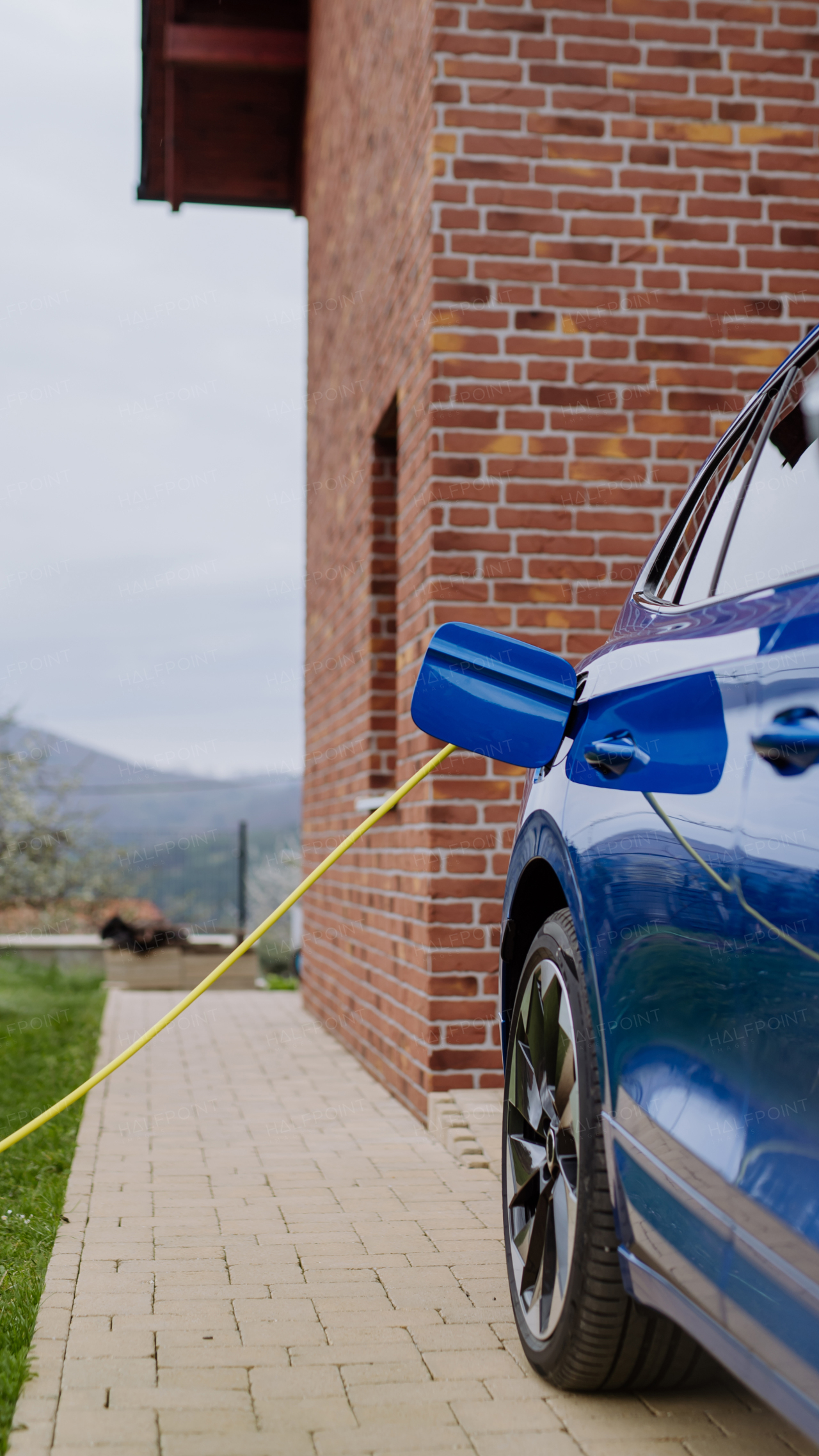 Close-up of electric car charging near a family house.