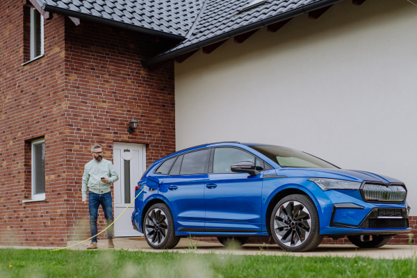 Mature man waiting for charging his new electric car.