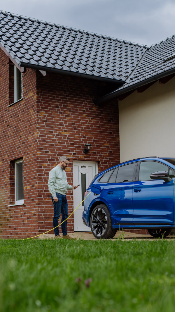 Mature businessman waiting for charging his new electric car.