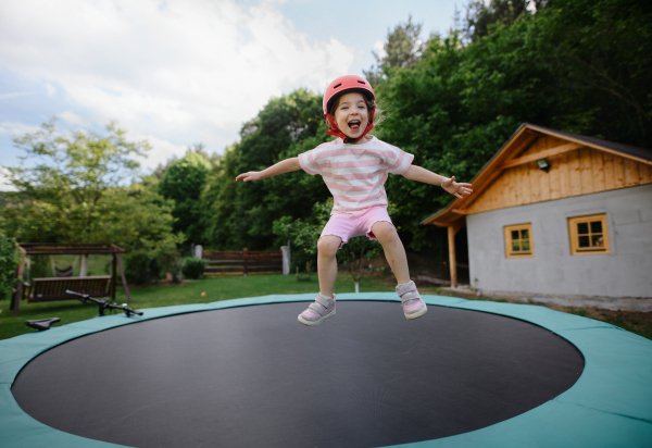 A little child enjoys jumping on trampoline - outside in backyard