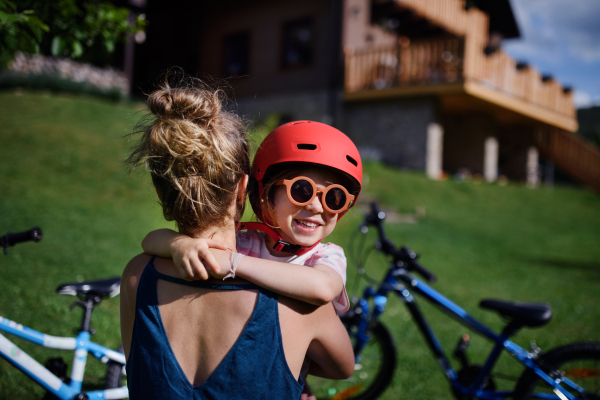 A young mother with little daughter preaparing for bike ride, putting on helmets