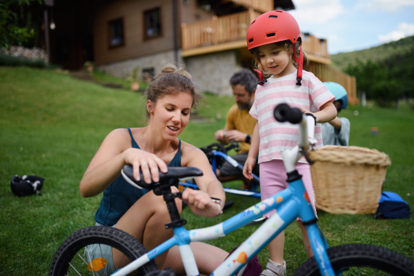 A young family with little children preaparing for bike ride, in front of house.