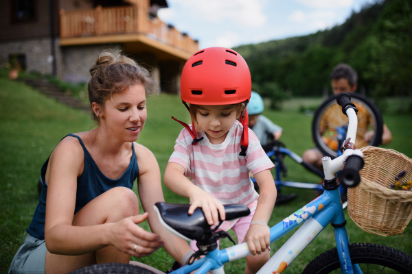 A young family with little children preaparing for bike ride, in front of house.