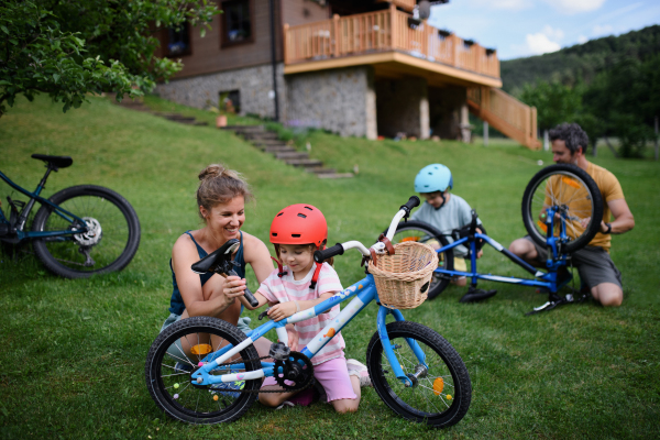 A young family with little children preaparing for bike ride, in front of house.