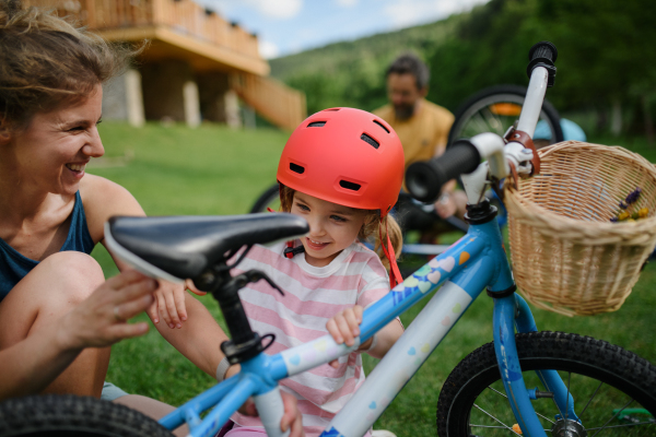 A young family with little children preaparing for bike ride, in front of house.