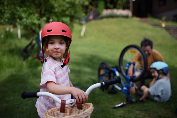 A young family with little children preaparing for bike ride, in front of house.