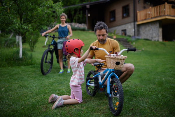 A young family with little children preaparing for bike ride, in front of house.