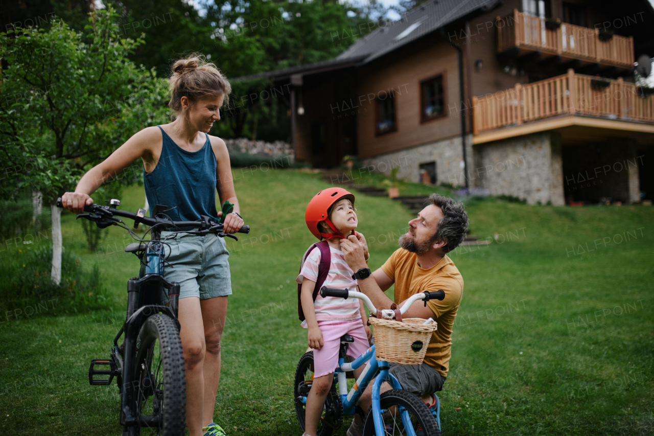 A young family with little children preaparing for bike ride, in front of house.