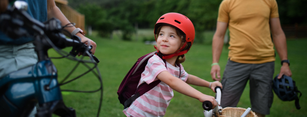 A young family with little children preaparing for bike ride, in front of house.