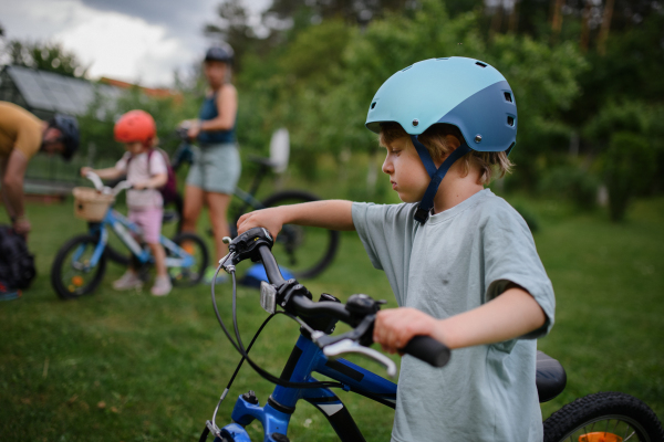 A young family with little children preaparing for bike ride, in front of house.