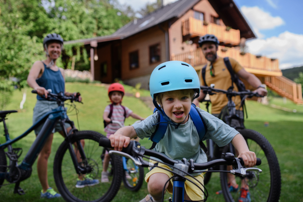 A young family with little children preaparing for bike ride, in front of house.