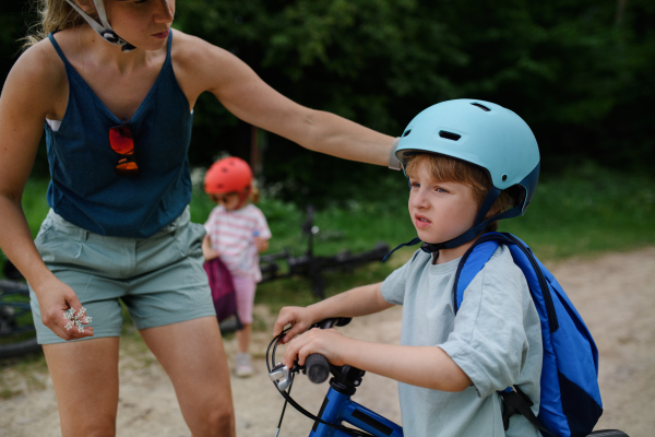 A portrait of young family with little children preapring for bike ride, standing with bicycles in nature.