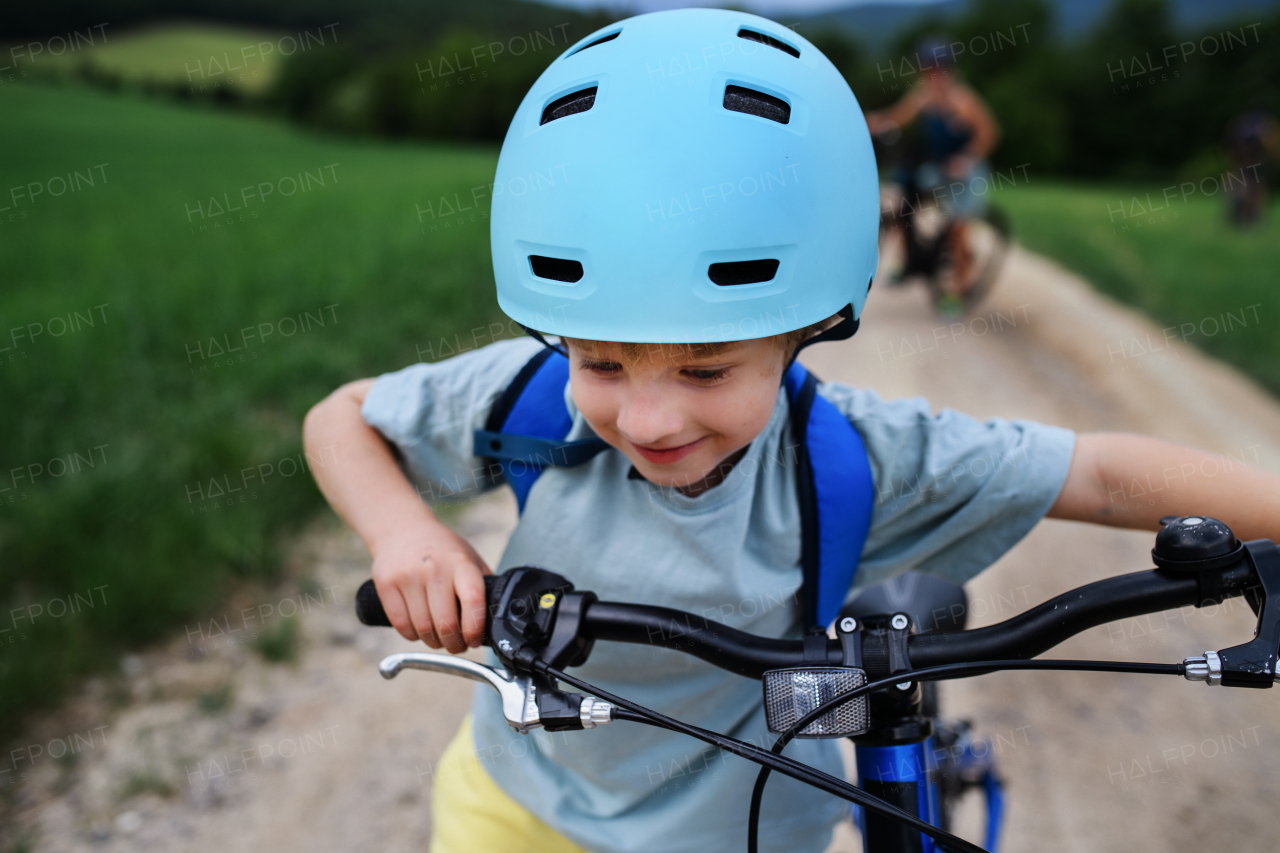 A young family with little child riding bicycles on road in village in summer.