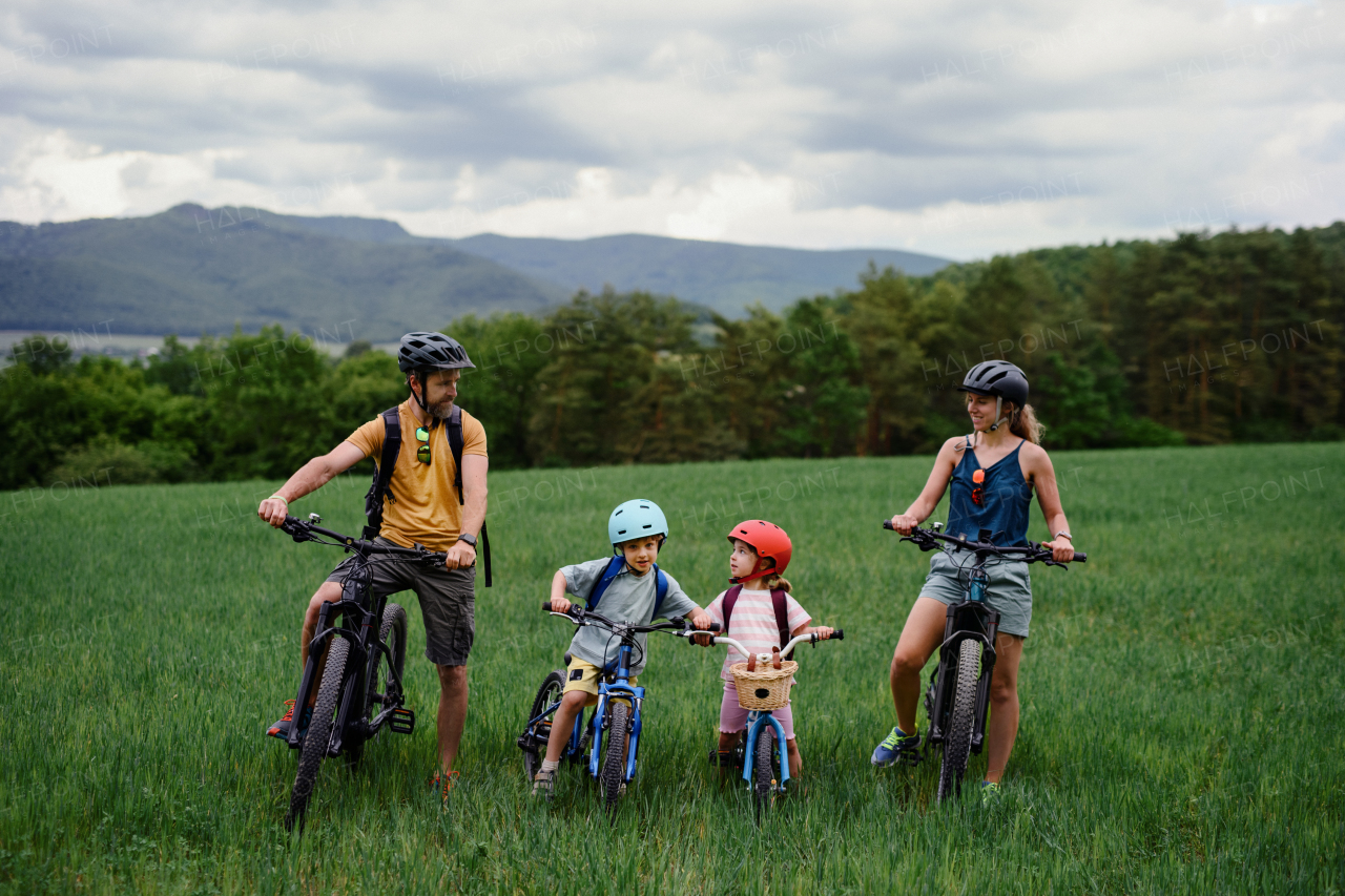 A portrait of young family with little children preapring for bike ride, standing with bicycles in nature.