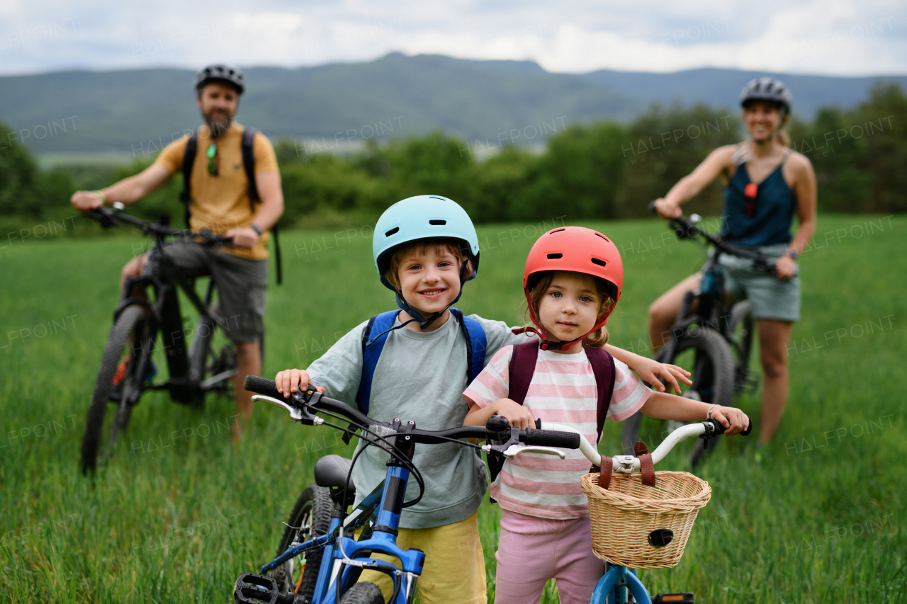 Portrait of young family with little children bicycling, standing and resting with the bicycles in nature.