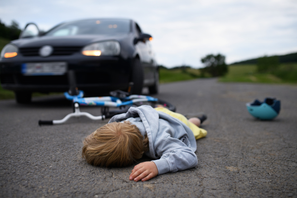 A little boy fallen from bicycle after car accident and helmet on road