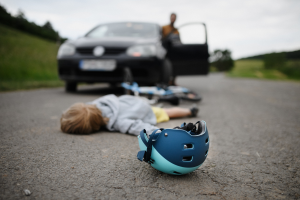 A little boy fallen from bicycle after car accident and helmet on road