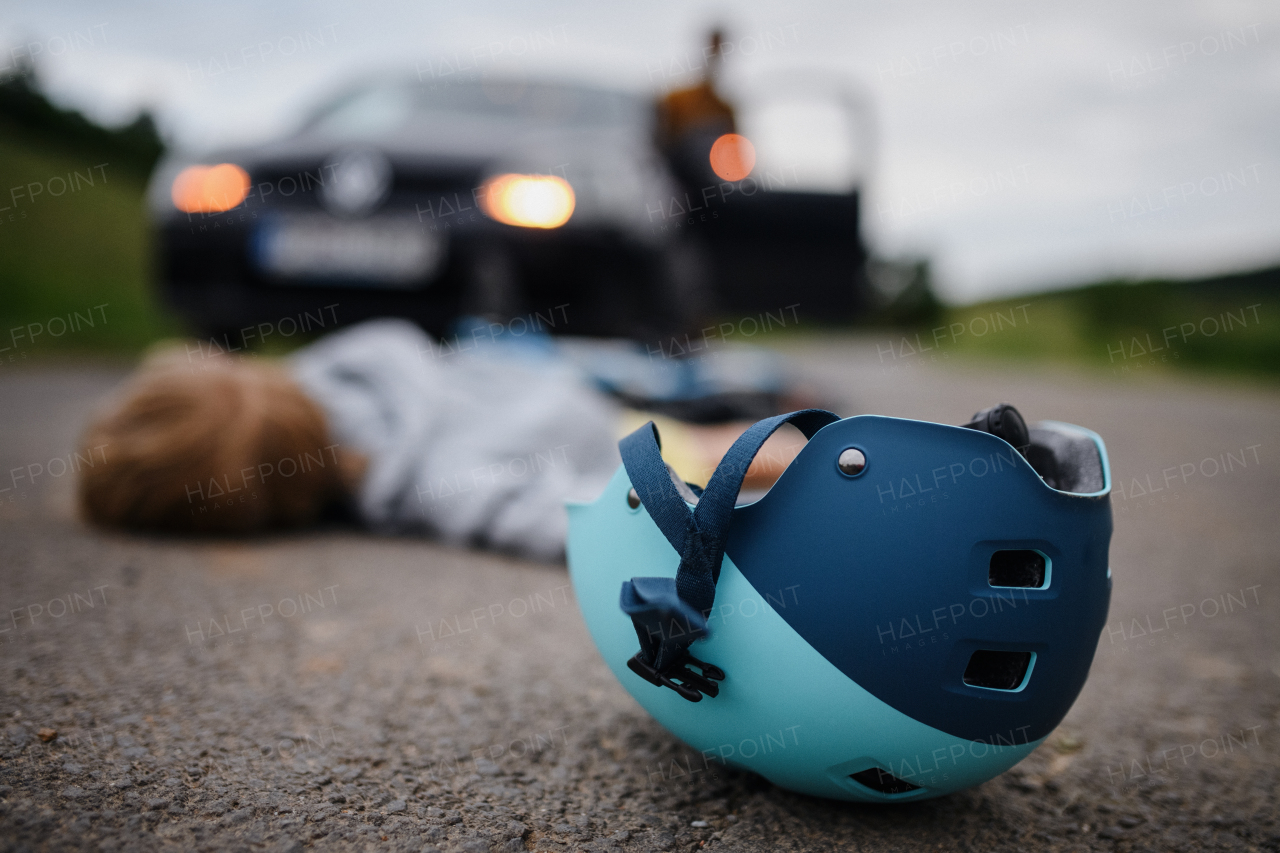 A little boy fallen from bicycle after car accident and helmet on road