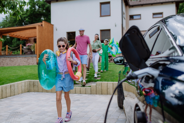 Happy family preparing for a holiday while their electric car charging.