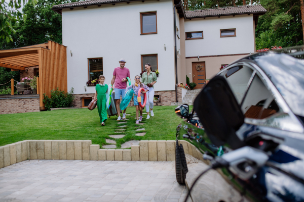 Happy family preparing for a holiday while their electric car charging.