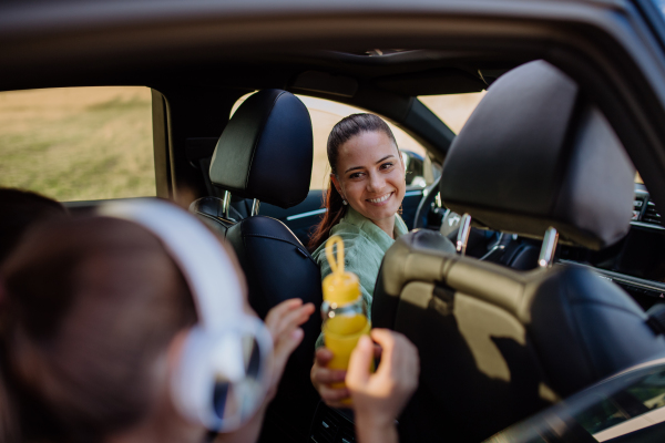 Young mother and little daughter having fun in their electric car.