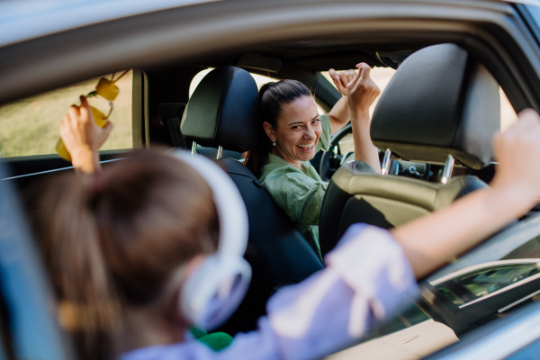 Young mother and little daughter having fun in their electric car.