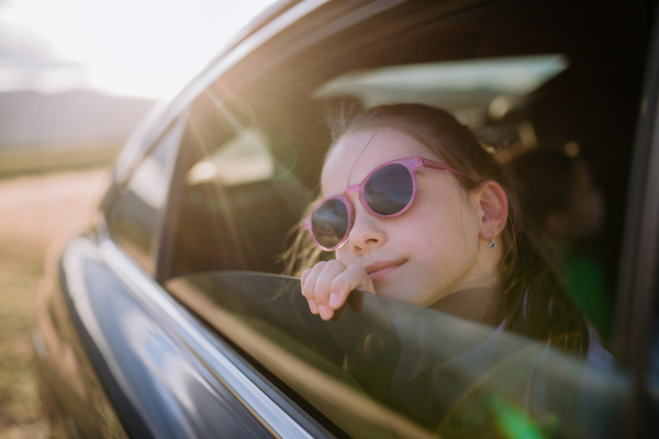 Little girl looking out of a car window during the ride.