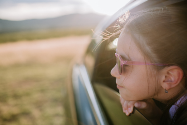 Little girl looking out of a car window during the ride.