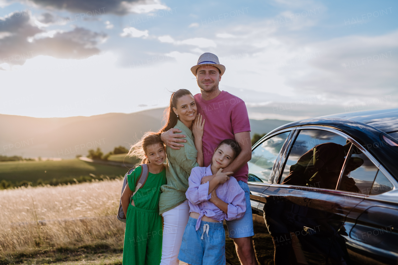 Happy family on a car trip having break in nature, next their electric car.