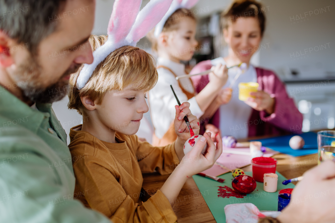 Happy family with little kids decorating easter eggs in their home.