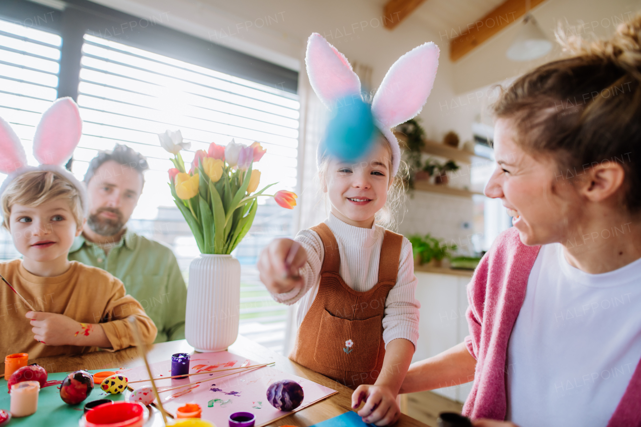 Happy family with little kids decorating easter eggs in their home.