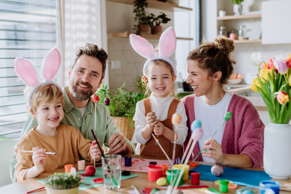 Happy family with little kids decorating easter eggs in their home.