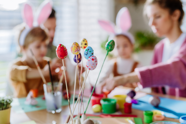 Happy family with little kids decorating easter eggs in their home, close-up.