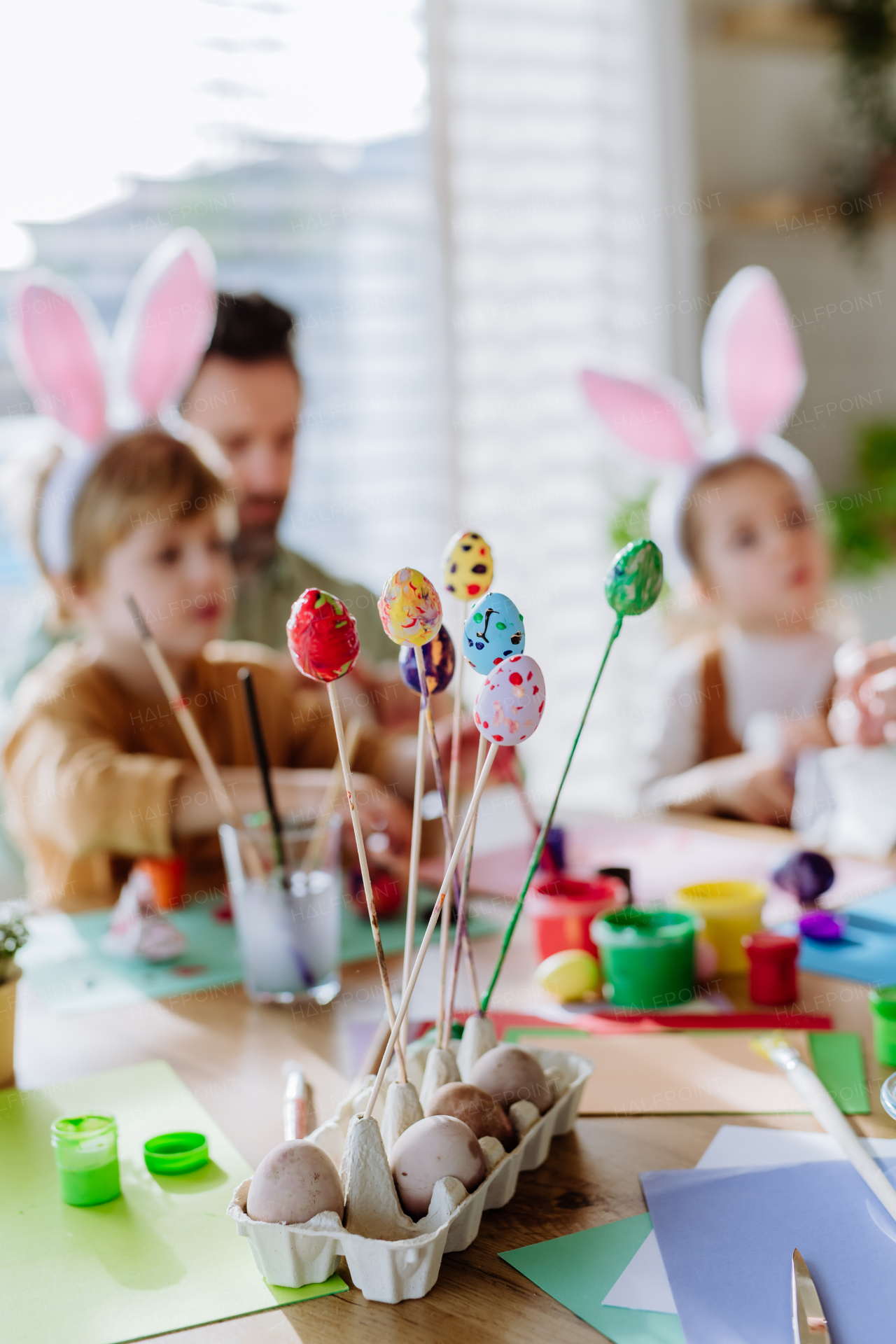 Happy father with little kids decorating easter eggs in their home.