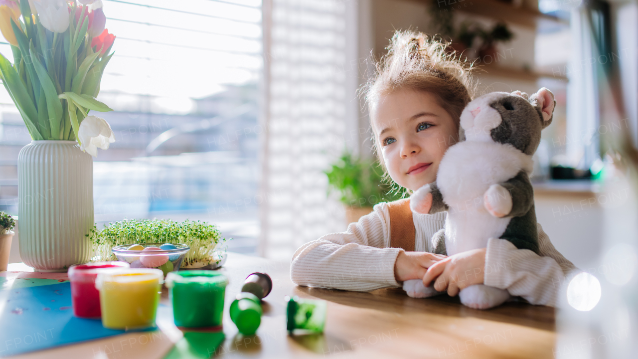 Portrait of little girl with bunny ears, bunny soft toy, celebrating easter and spring.