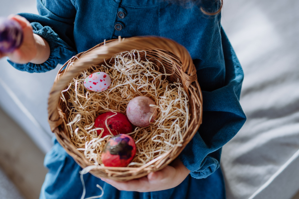 Top view of little girl holding basket with the easter eggs.