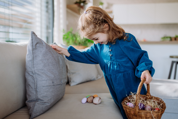 Happy little girl looking for easter eggs in their home.