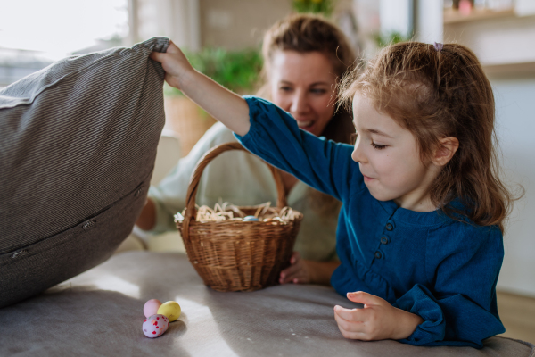 Happy little girl looking for easter eggs in their home.