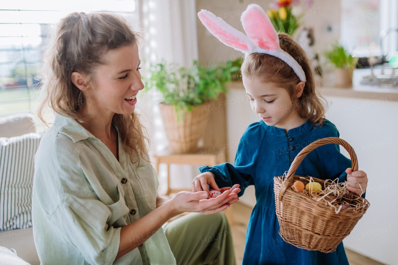 Little girl with bunny ears holding basket and showing mother easter eggs which she found.