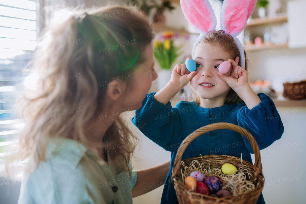 Happy little girl with bunny ears showing easter eggs to her mother.