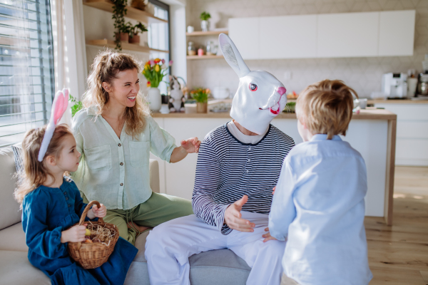 Little children having fun with her mum and Easter rabbit, celebrating Easter.