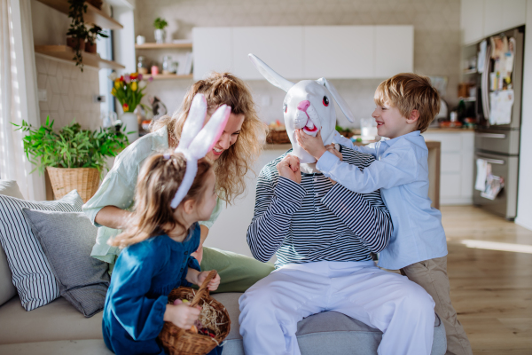 Little children having fun with her mum and Easter rabbit, celebrating Easter.