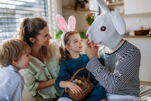 Little children having fun with her mum and Easter rabbit, celebrating Easter.