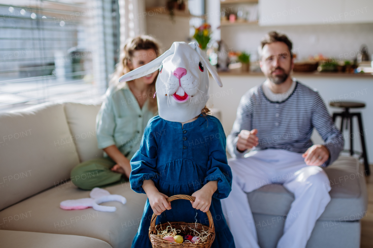 Little girl with rabbit mask celebrating spring with her parents at home.