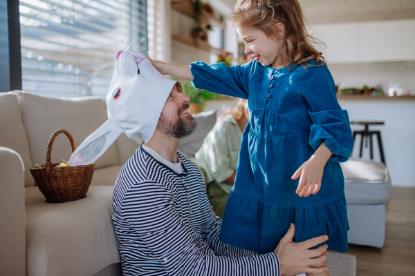 Little children having fun with her dad in Easter rabbit mask, celebrating Easter.