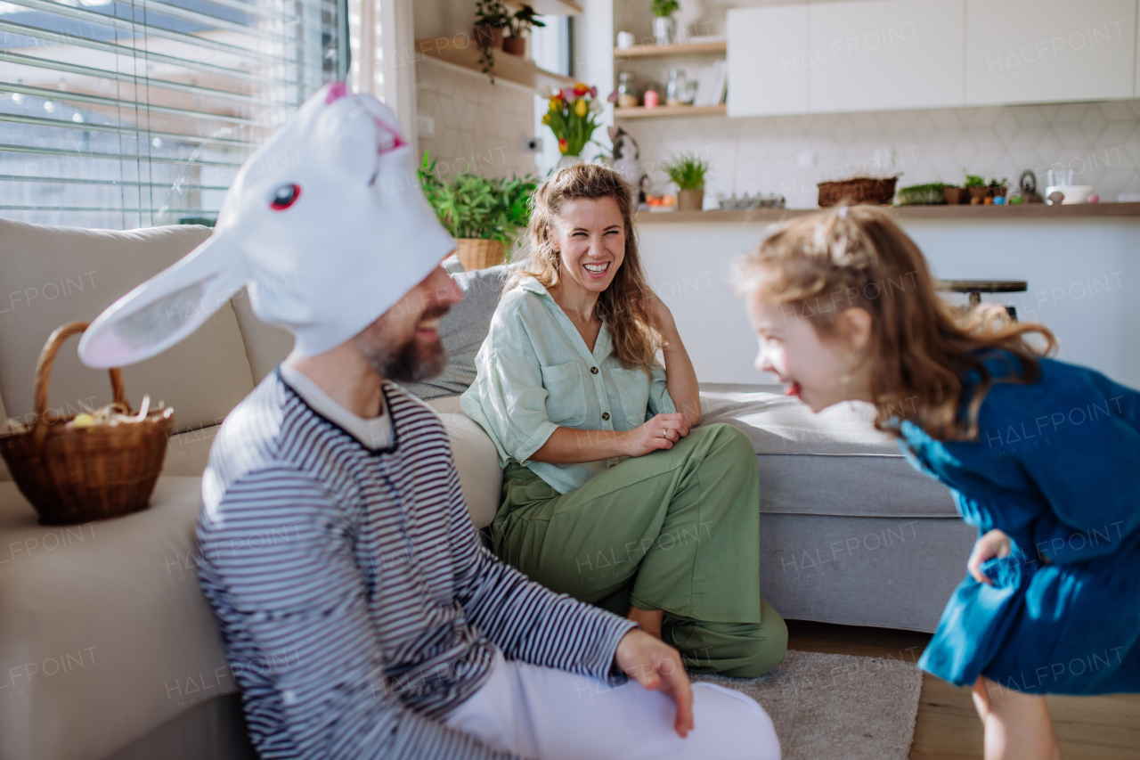 Little children having fun with her mum and father with Easter rabbit mask, celebrating Easter.