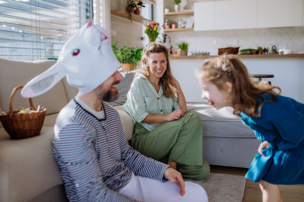 Little children having fun with her mum and father with Easter rabbit mask, celebrating Easter.