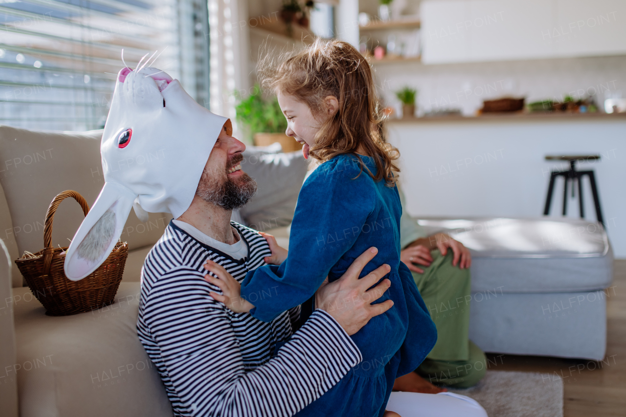 Little girl having fun with her father, who is wearing Easter rabbit costume.